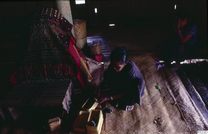 Attendants beside a textile-draped corpse