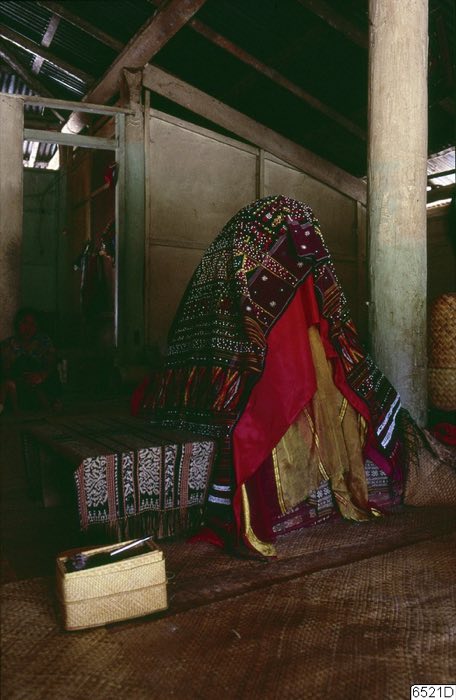 Corpse seated, covered in funeral textiles