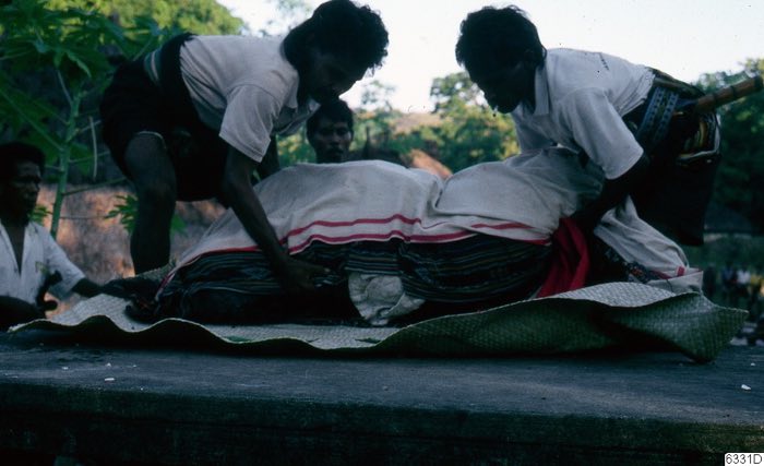 Men wrapping a corpse in textiles
