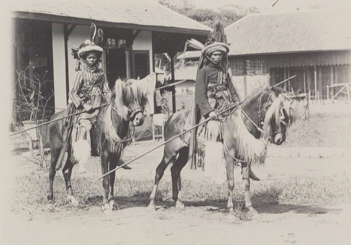 Two riders in decorated head-wraps carrying spears